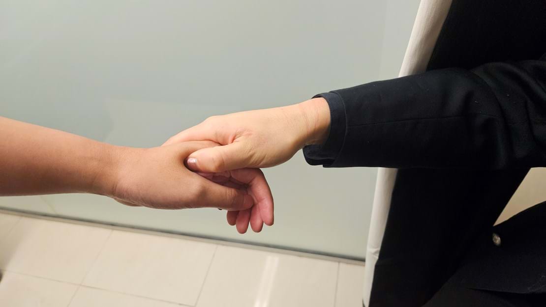 Two people shaking hands in a professional TCM or acupuncture clinic setting.