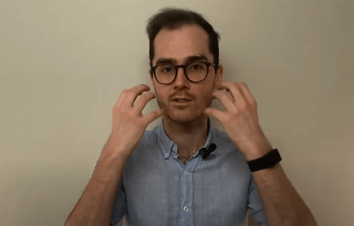 Man in glasses gestures while discussing TCM near his face, speaking to the camera.